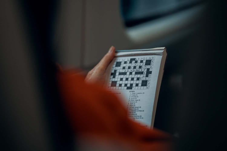 En person løser et kryssord i en avis. Foto Pexels