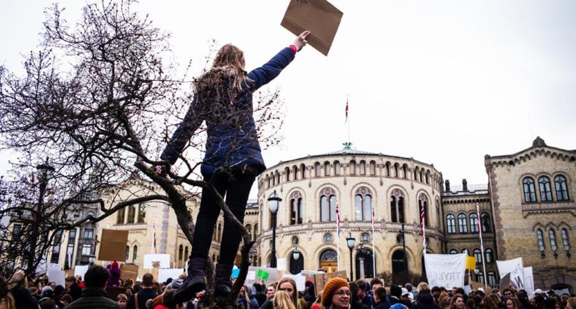 En kvinne står foran en forsamling som demonstrerer foran det norske Stortinget.