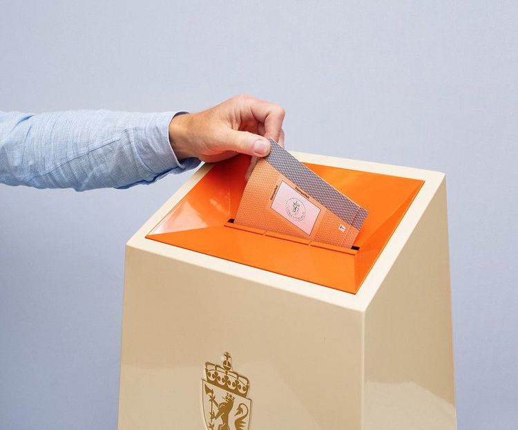 Øverste del av valgurne. En hånd er i ferd med å slippe en stemmeseddel ned i.