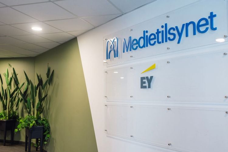 Bilde fra inngangspartiet til Medietilsynets kontor. Det er grønn vegg og to grønne planter, og på et hvitt felt på veggen står Medietilsynets logo øverst.