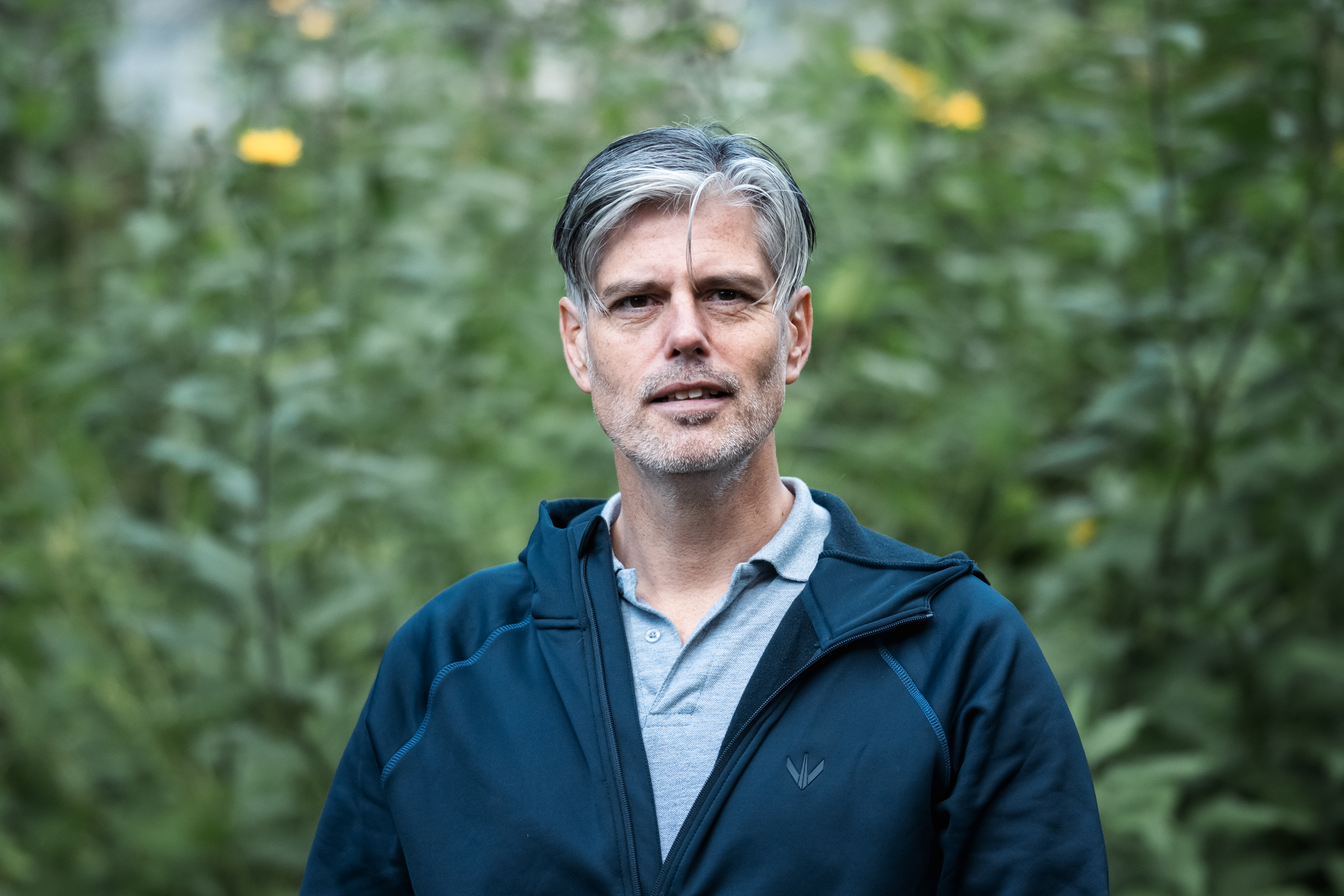 Bilde av Håvard Tjora som står foran grønne busker utendørs