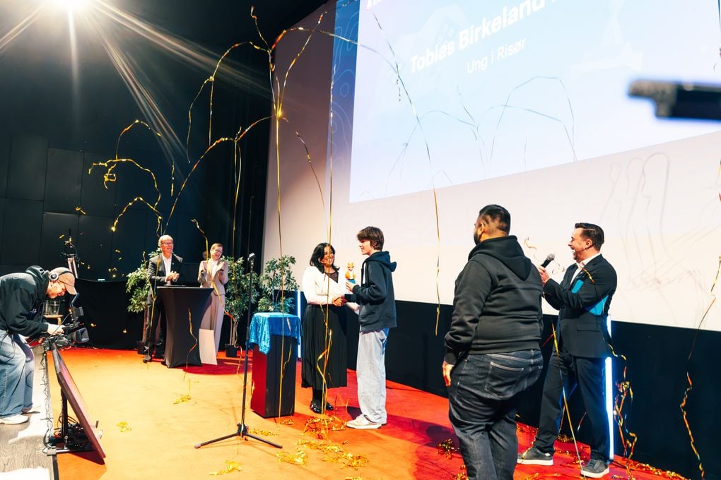 Tobias Birkeland Hovet tar imot Ibelinprisen av kultur- og likestillingsminister Lubna Jaffery. I luften er det konfetti for vinneren.