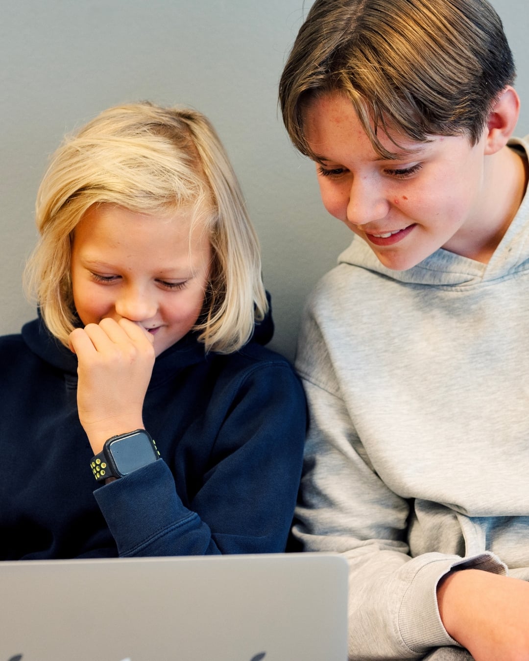 To barn sitter sammen og ser på en bærbar PC.