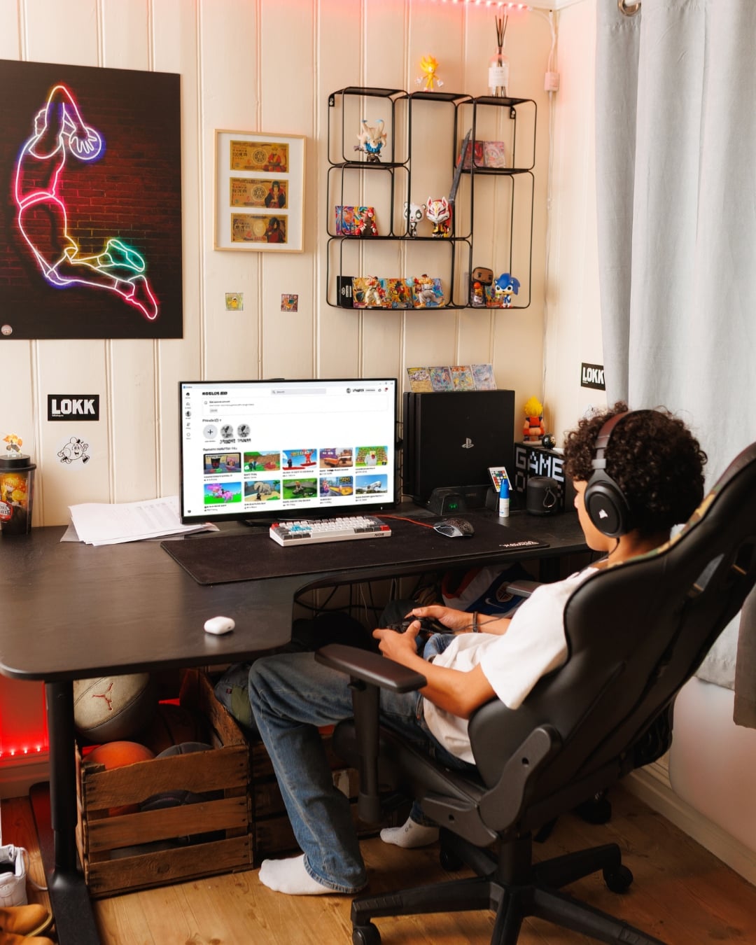 En ungdom sitter ved en PC med hodetelefoner og spiller Roblox ved et skrivebord på et soverom.