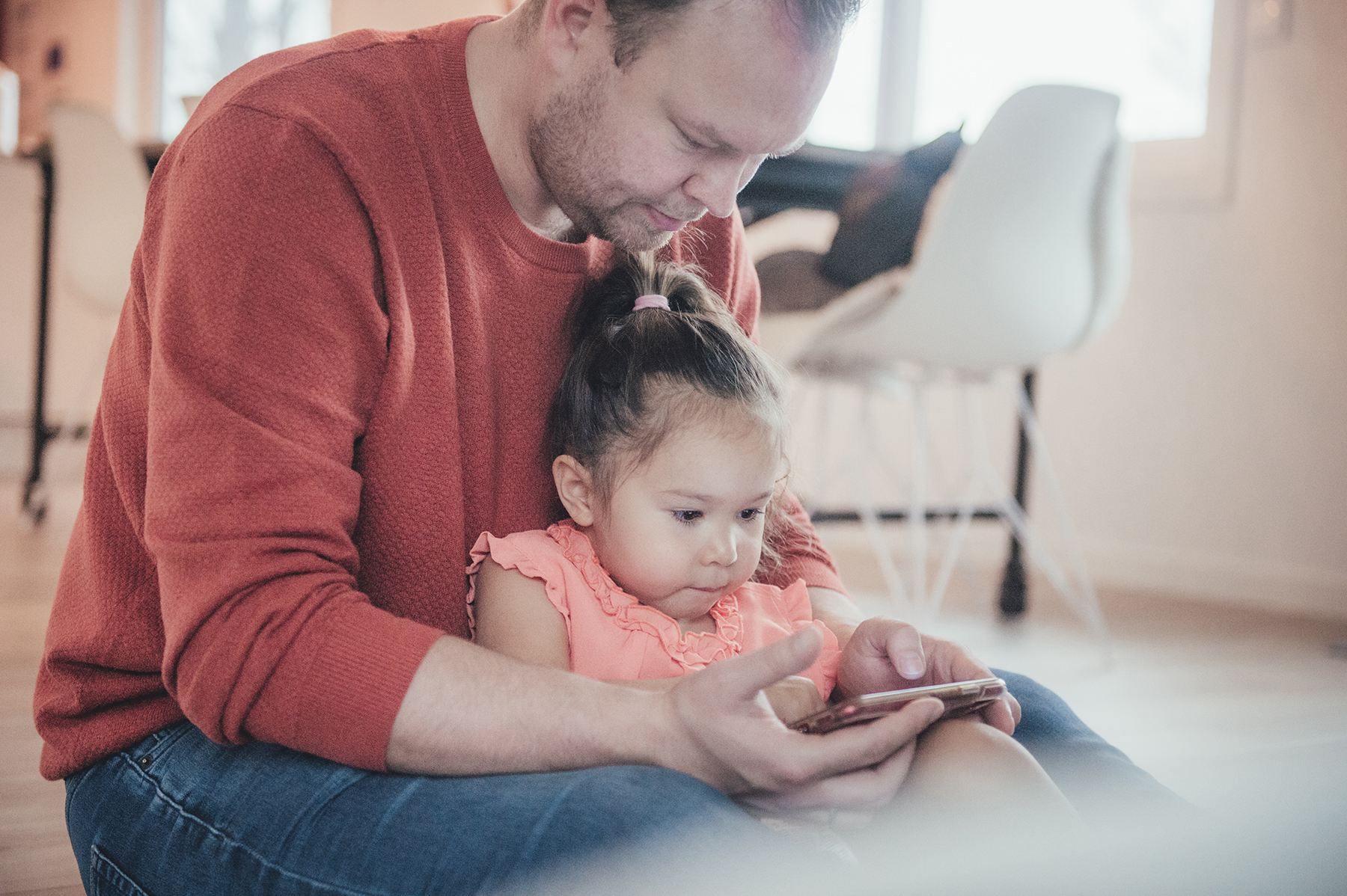 Bildet viser en far med sin lille datter i fanget. Sammen ser de på mobilen. Foto Kine Jensen/ Medietilsynet