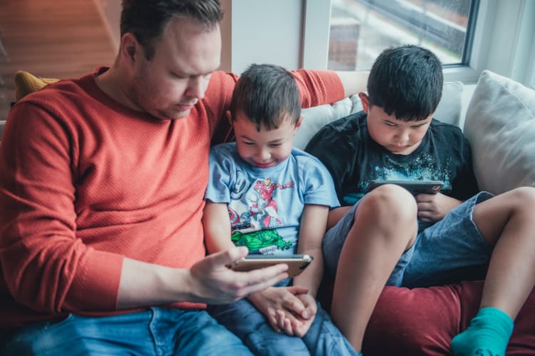 En far sitter sammen med sønnene sine og er på mobilen. Foto Kine Jensen/ Medietilsynet