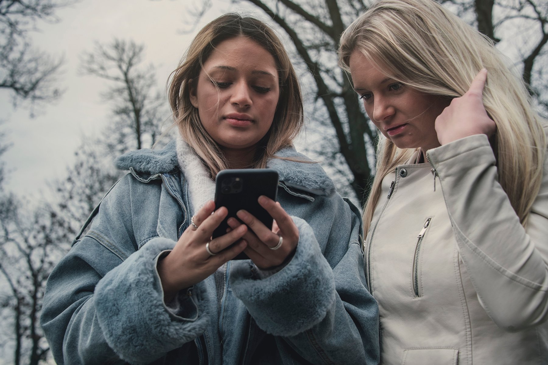 To tenåringsjenter står sammen og ser på en mobil. Foto Kine Jensen/ Medietilsynet