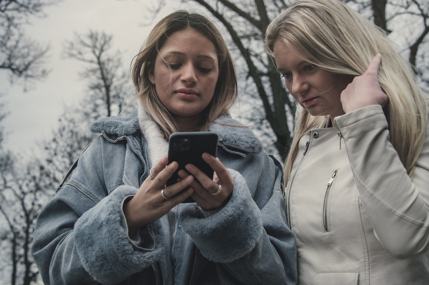 To tenåringsjenter står sammen og ser på en mobil. Foto Kine Jensen/ Medietilsynet