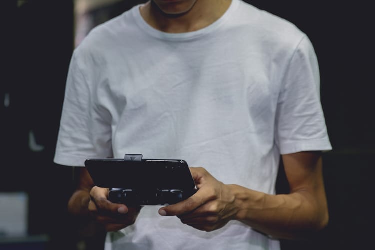 En tenåringsgutt holder i en konsoll og spiller dataspill. Foto Pexels