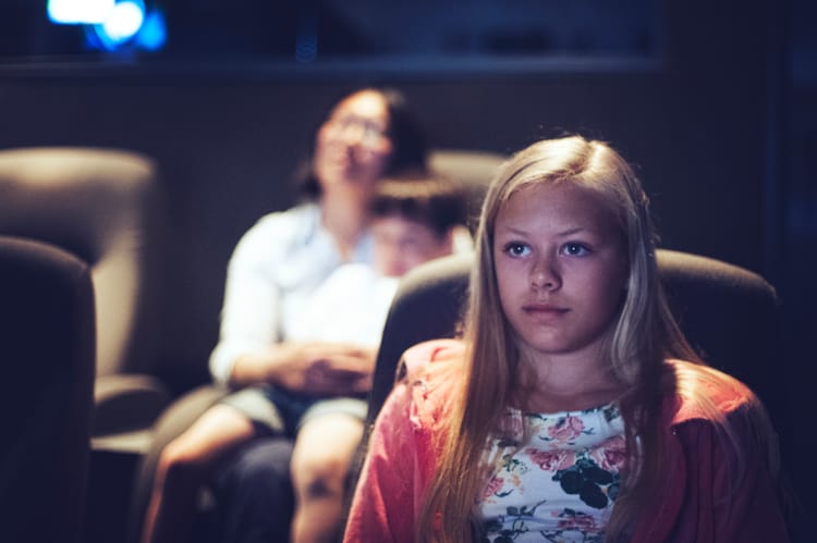 En tenåringsjente og mor og barn ser på film på kino. Foto Medietilsynet