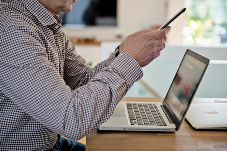 Mann på PC og mobil. Foto: Kine Jensen/Medietilsynet