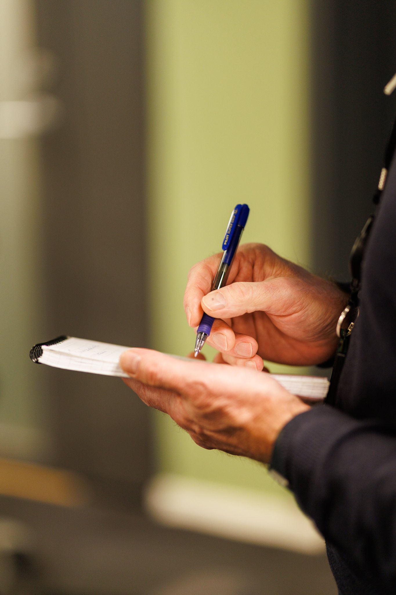 H&aring;nd skriver notater med penn p&aring; en liten notatblokk.