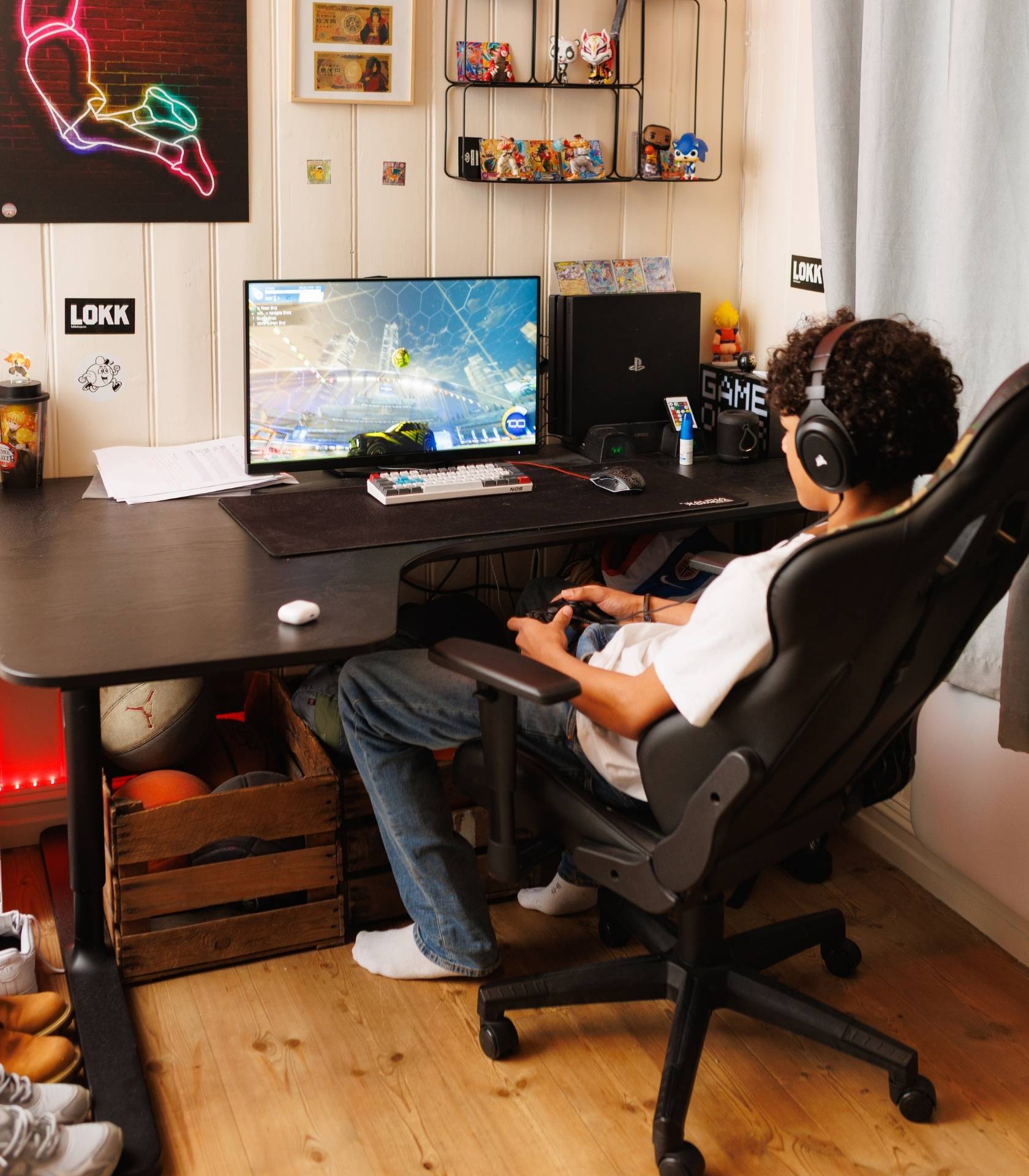 Ung person sitter ved en gaming-PC med hodetelefoner og håndkontroll og spiller et bilbasert videospill.