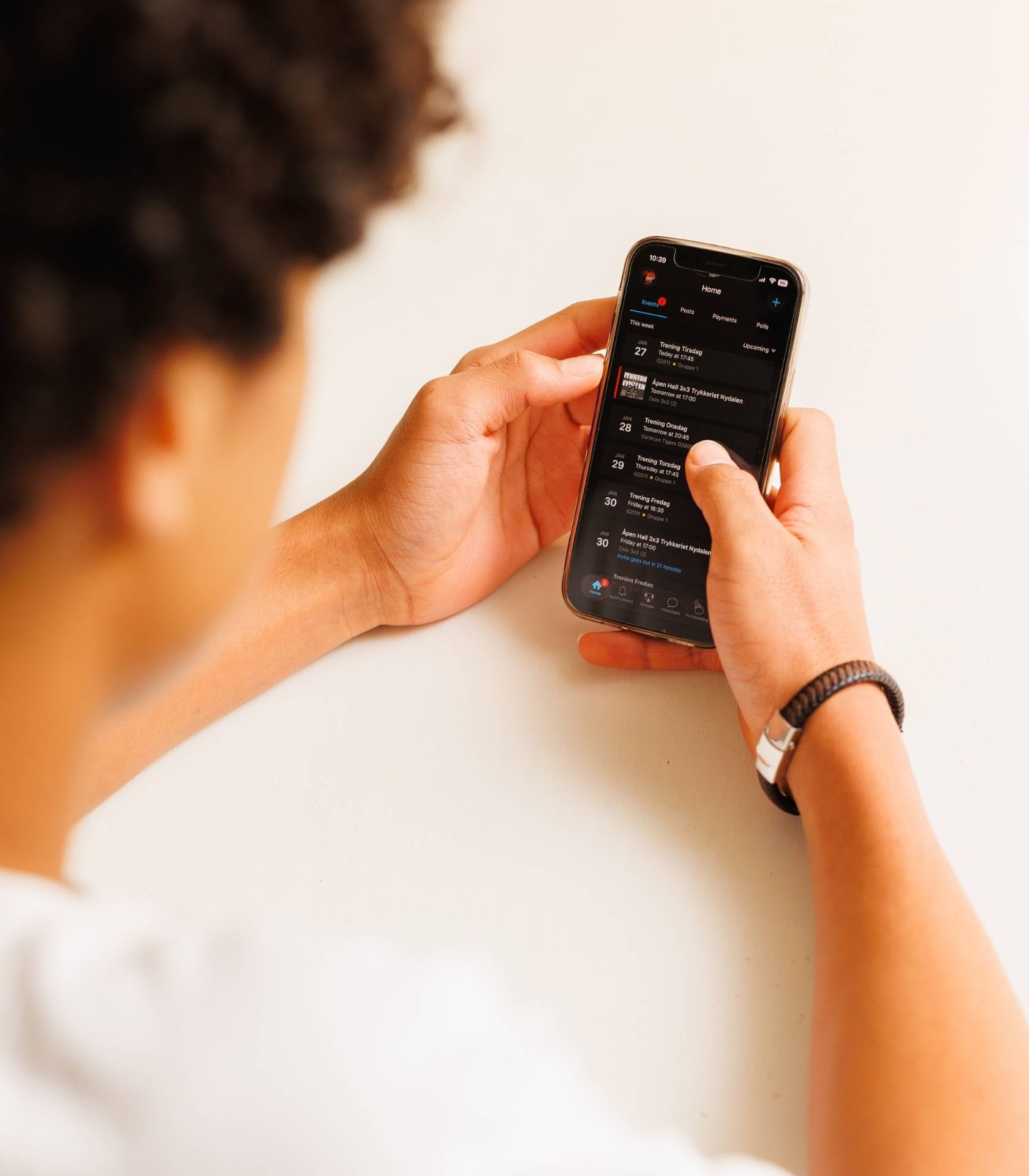 Ung person holder en mobiltelefon og ser på en oversikt over kommende aktiviteter og arrangementer i en app.